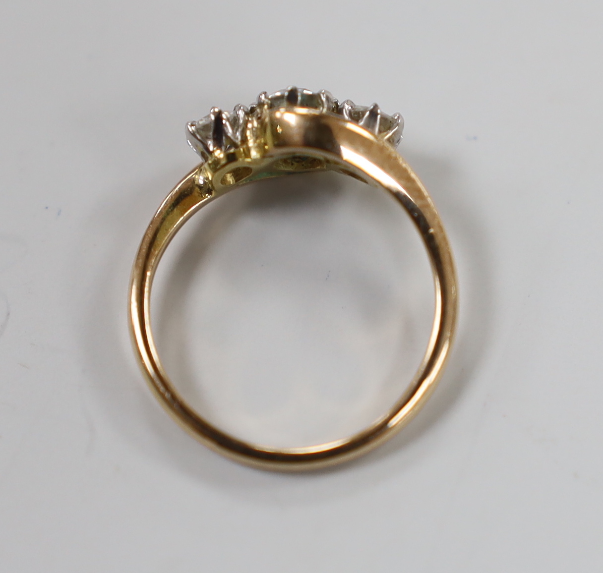 A 14k and three stone diamond set crossover ring, size H, gross weight 2 grams.